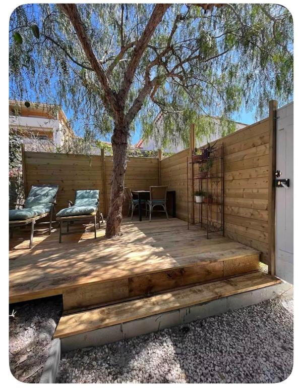 une terrasse en bois avec un arbre et deux chaises dans l'établissement Atelier, à Saint-Mandrier-sur-Mer