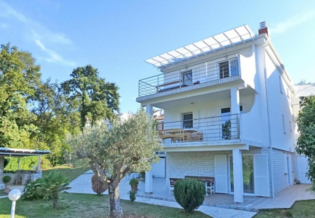 a white house with a balcony and a tree at Apartments Vlado in Njivice