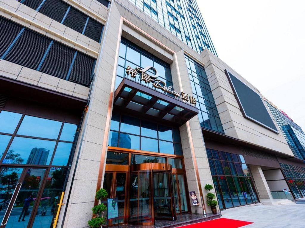 un grand bâtiment avec des fenêtres en verre et une porte tournante dans l'établissement Xana Deluxe Hotel Chongqing Tongliang Wanda Plaza Longcheng Tiandi, à Tongliang