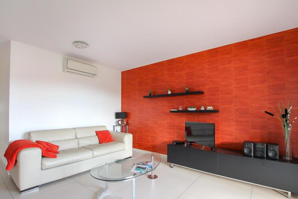 - un salon avec un canapé blanc et un mur rouge dans l'établissement NEPTUNE - Apartment 4 to 6 people - Port of Porto-Vecchio, à Porto-Vecchio