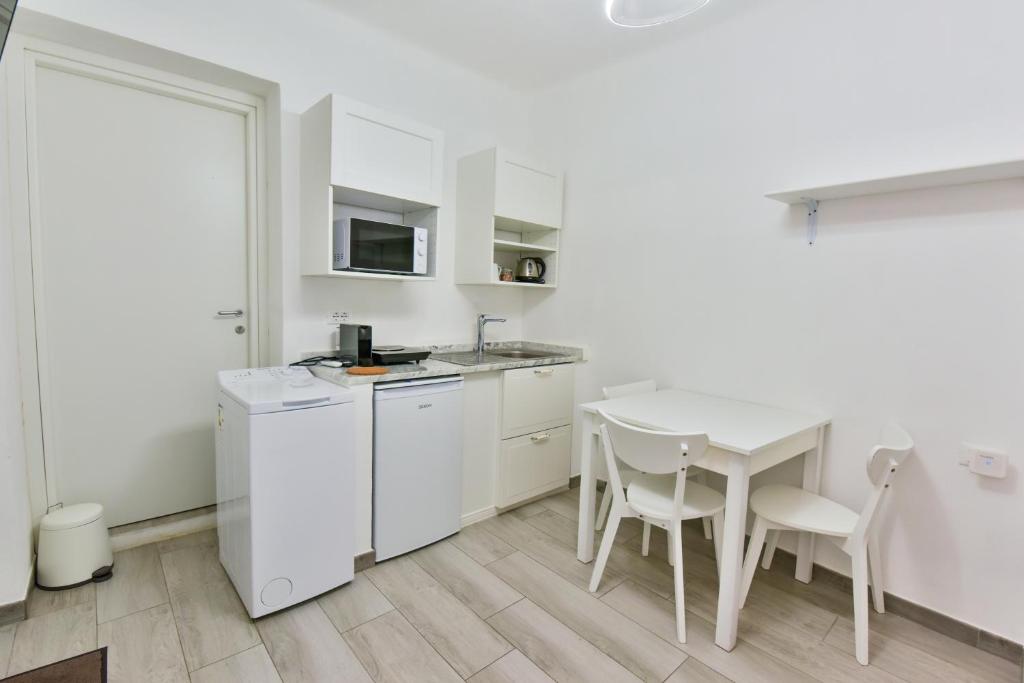 a kitchen with white cabinets and a table and chairs at VILLA IRMA in Varigotti