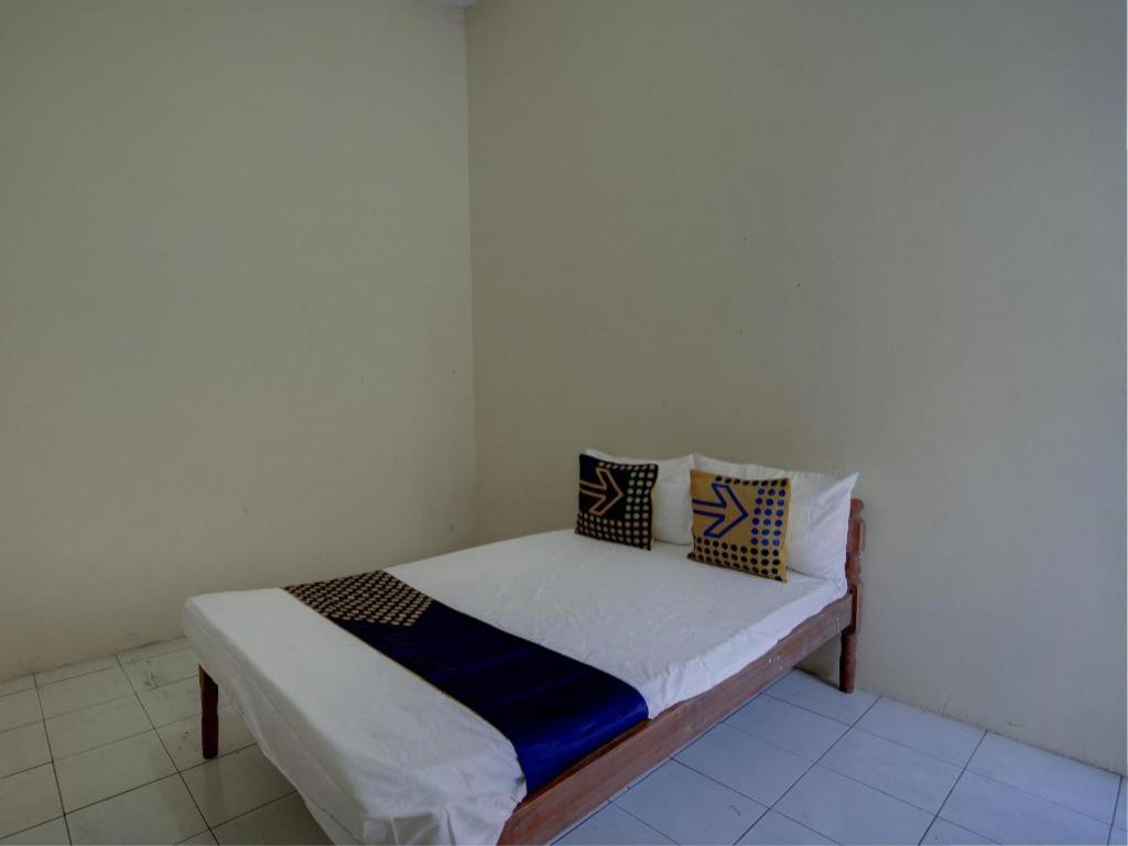 Una cama pequeña con almohadas en una habitación. en Hotel O Sunyoto Homestay Syariah, en Banjarsalero