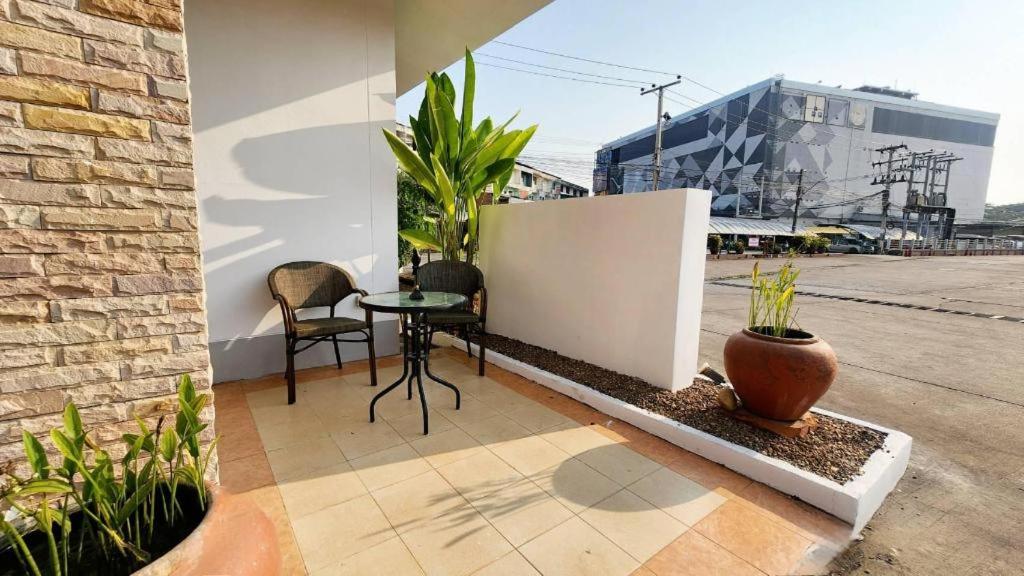 a patio with two chairs and a table and some plants at Mark Four Place Hotel in Phrae