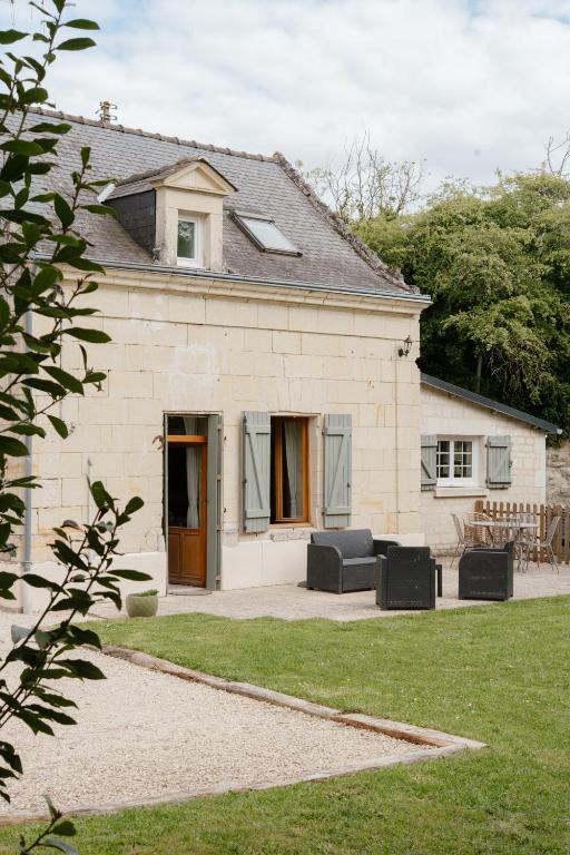 une maison en pierre avec deux meubles en cuir noir devant dans l'établissement Gîte Les Caves aux Fièvres - Maison avec jardin près de Chinon, à Beaumont-en-Véron