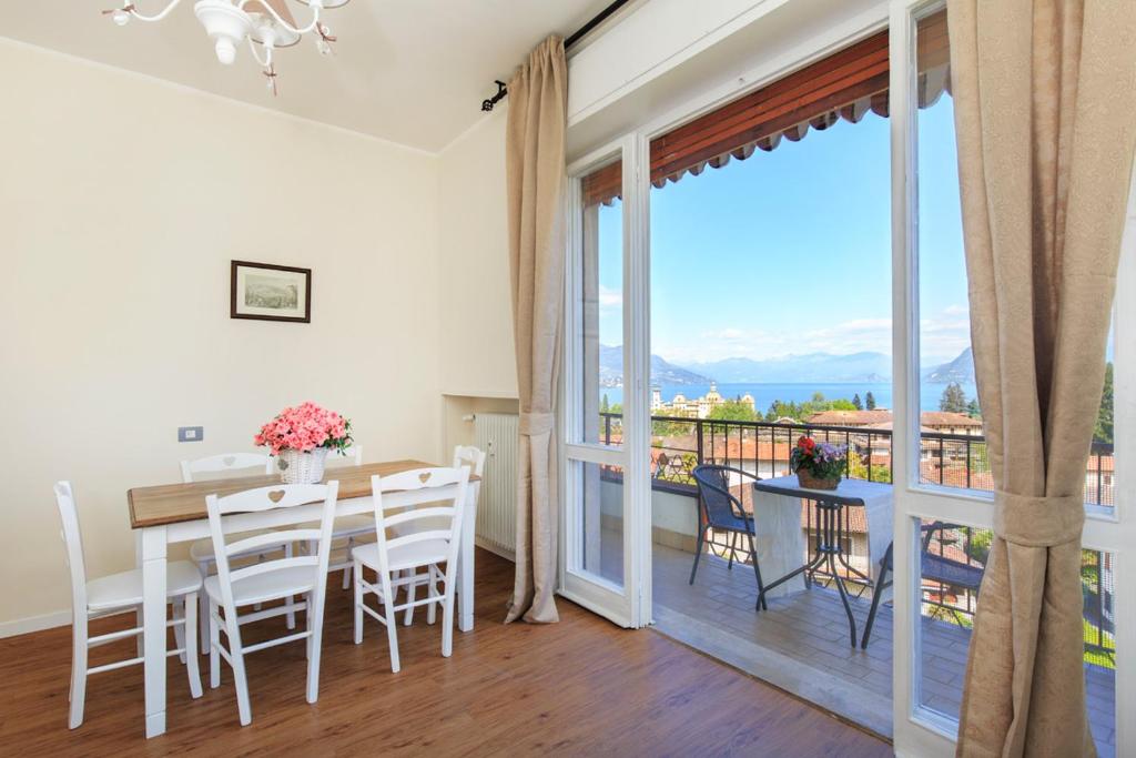 ein Esszimmer mit einem Tisch und Stühlen sowie einem Balkon in der Unterkunft Costa Azzurra by Impero House in Stresa