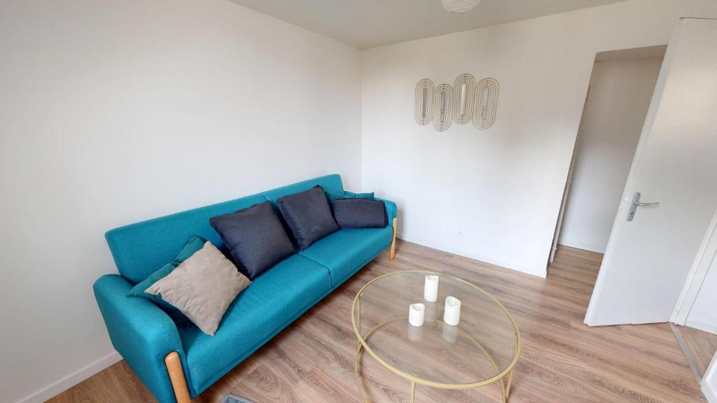 un salon avec un canapé bleu et une table en verre dans l'établissement Magnifique appartement Bastion, au Havre