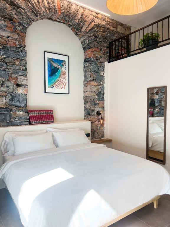 a bedroom with a white bed and a brick wall at La Campanula in La Spezia