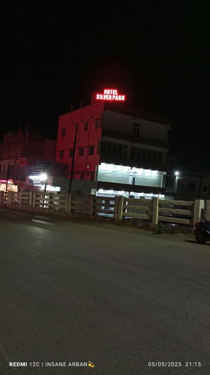 Un edificio con un letrero de neón frente a él por la noche. en Hotel Silver Park and Restaurant, en Bilāspur