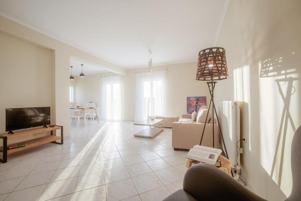 a living room with a couch and a tv and a table at Villa Du Vignoble in Zakynthos Town