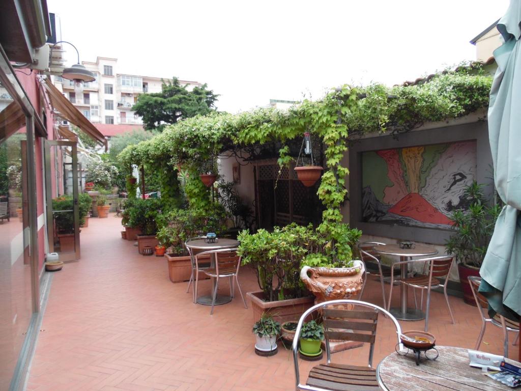 an outdoor patio with tables and chairs and plants at Agorà Hostel in Pompei