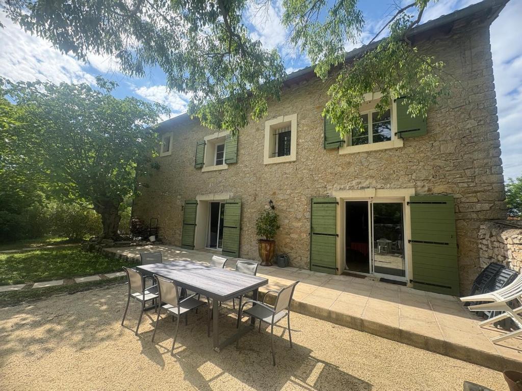 Una mesa y sillas frente a una casa en Bastide Terrieu - domaine avec piscine et terrain de boules, climatisation, en Saint-Mathieu-de-Tréviers