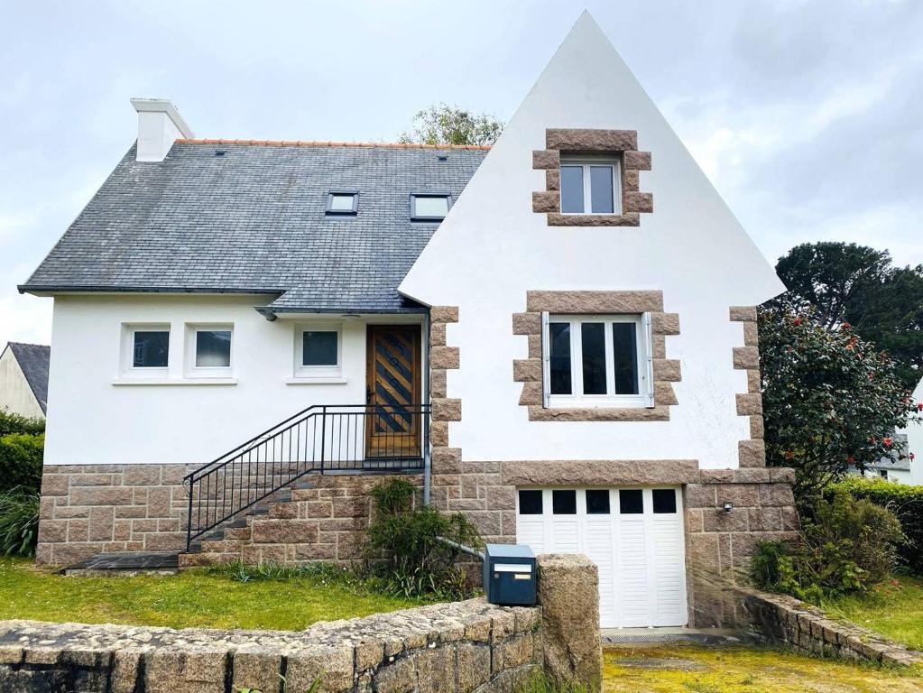 une maison blanche avec un toit pointu dans l'établissement Maison avec WIFI, jardin à 320m de la plage à TREGASTEL - Réf 183, à Trégastel