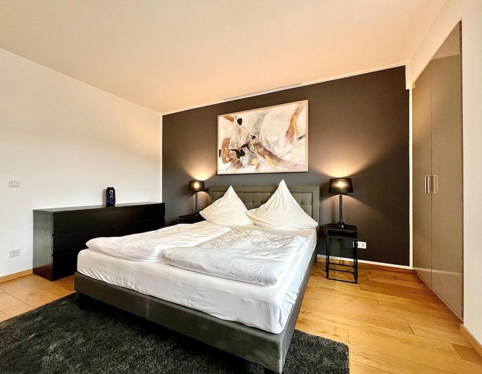 ein Schlafzimmer mit einem weißen Bett und einem Gemälde an der Wand in der Unterkunft Balkon und Eleganz Düsseldorf in Düsseldorf