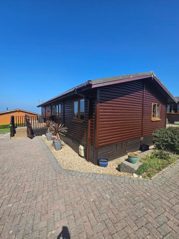 a large wooden cabin with a brick driveway at Ocean View Lodge - Sea Views & Decking in Ilfracombe