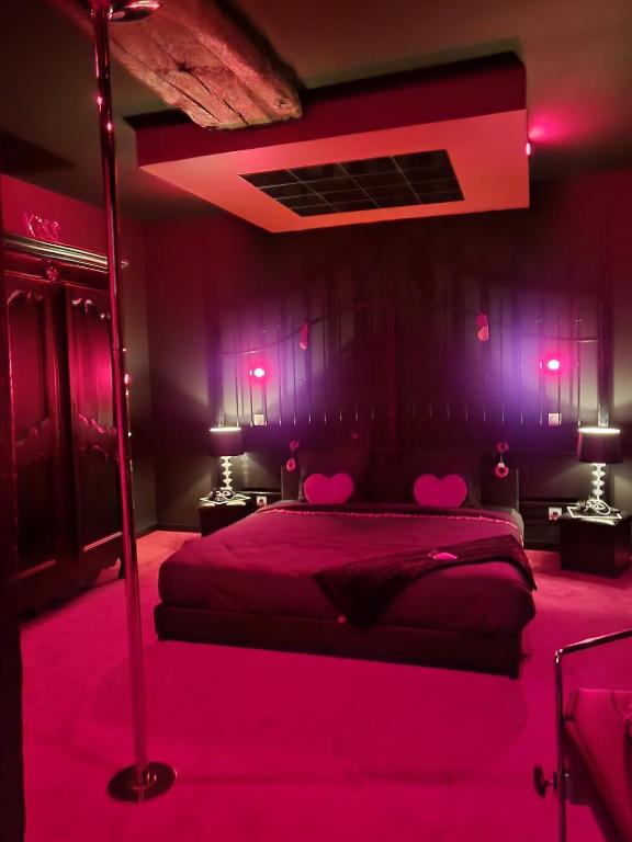 une chambre avec un lit avec des lumières roses dessus dans l'établissement Gîte romantique Le GLAMOUR, à Mazé