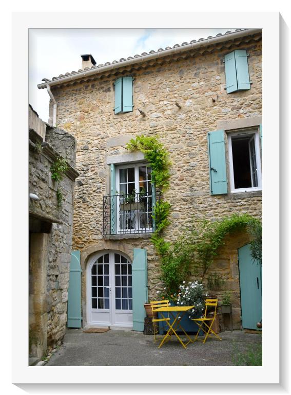 un bâtiment avec une table et des chaises devant lui dans l'établissement La belle provençale, à Saint-André-de-Roquepertuis