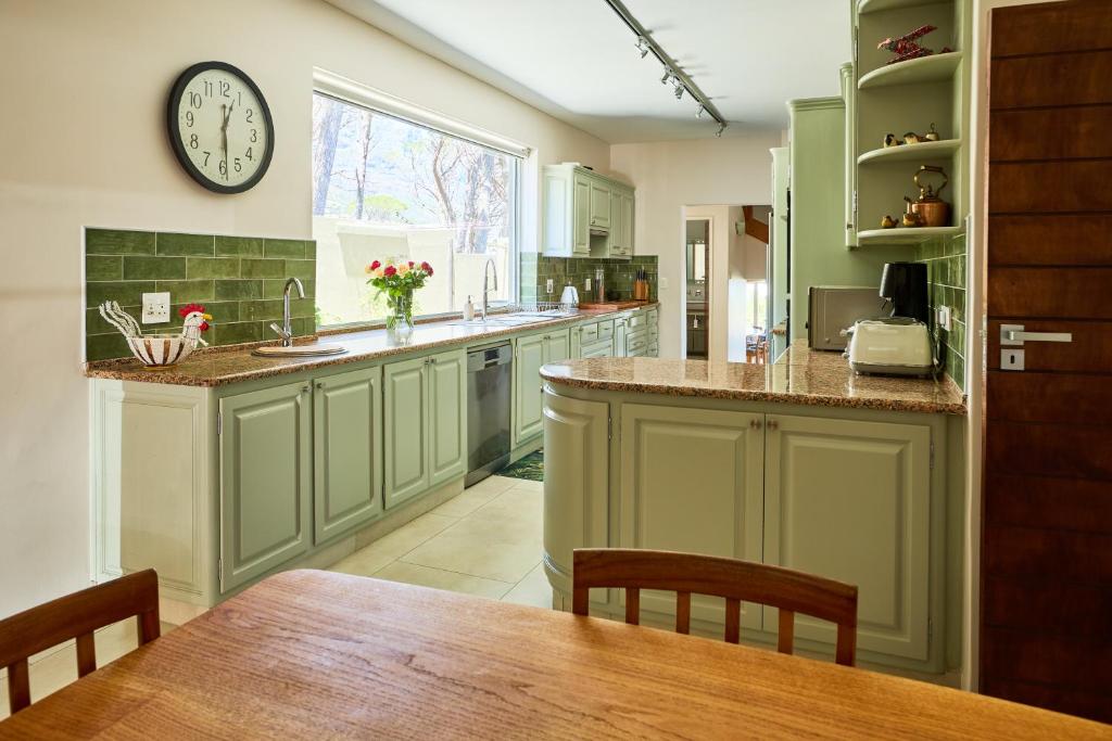a kitchen with green cabinets and a clock on the wall at 42 On Strathmore in Cape Town