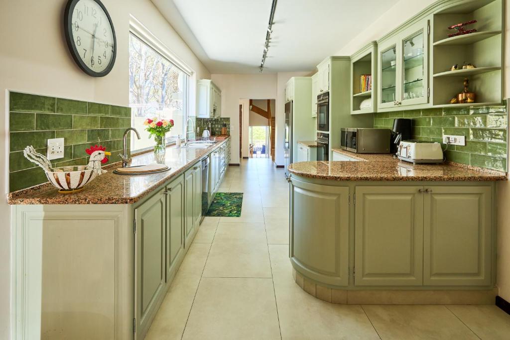 a kitchen with green cabinets and a large clock on the wall at 42 On Strathmore in Cape Town