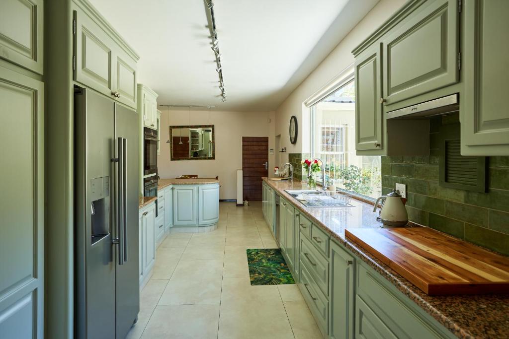 a large kitchen with green cabinets and a window at 42 On Strathmore in Cape Town