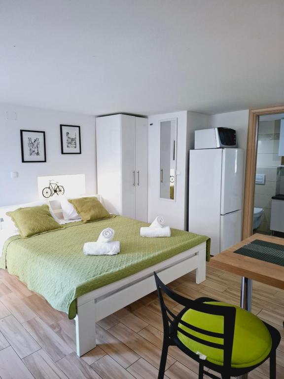 a bedroom with a bed and a chair and a refrigerator at Studio Jadro in Selce