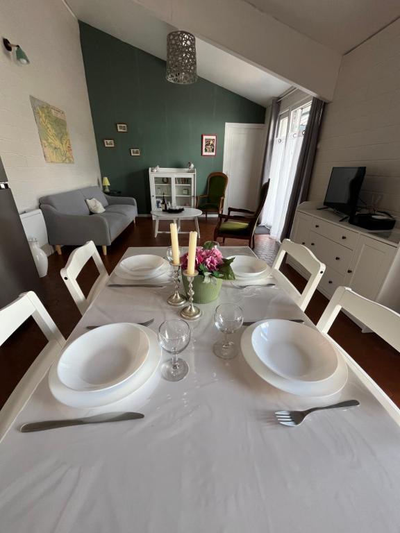 a dining room table with white plates and candles at Cottage les Écuries du faubourg in Béthune