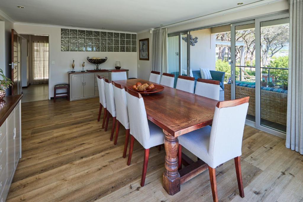 a dining room with a wooden table and white chairs at 42 On Strathmore in Cape Town