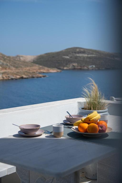 a table with plates of fruit on top of it at Helios Panormos Sea-View Retreat in Nisída Planítis