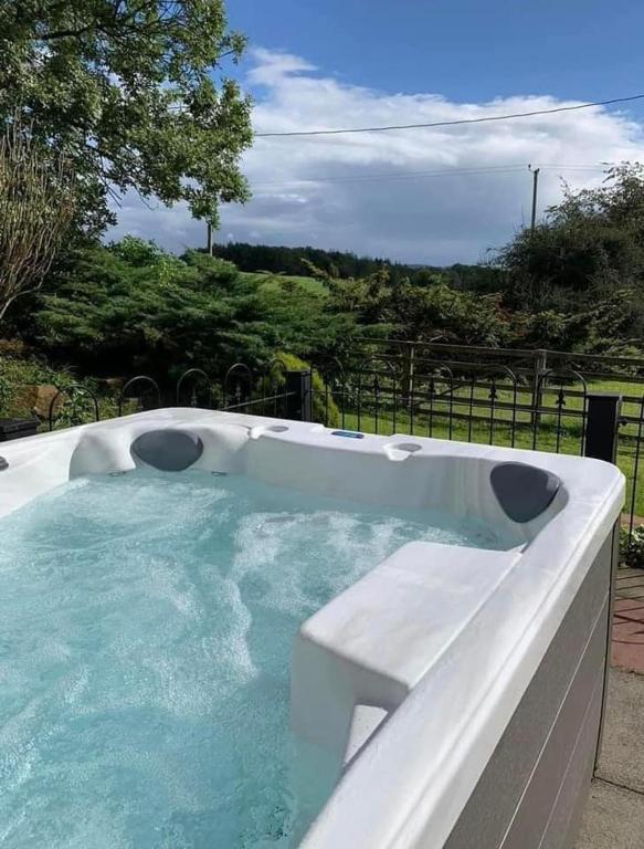 a hot tub in a yard next to a fence at Jane Welsh Cottage in Thornhill