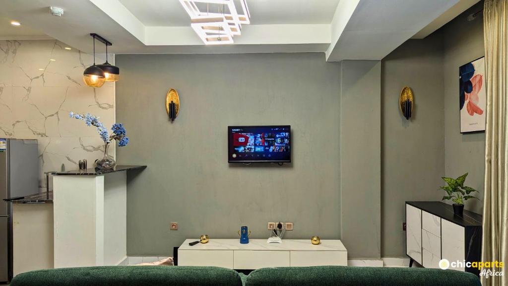 un salon avec un canapé et une télévision sur un mur dans l'établissement Studio chic avec parking près de l'aéroport, à Douala