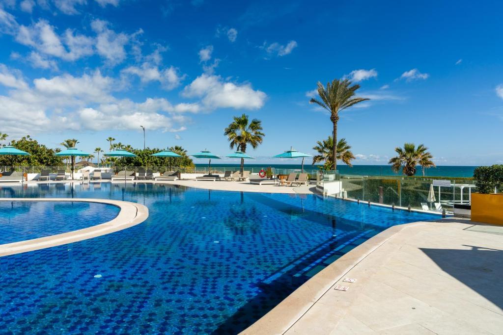 スースにあるSousse Pearl Marriott Resort & Spaのヤシの木と海を望む大型スイミングプール