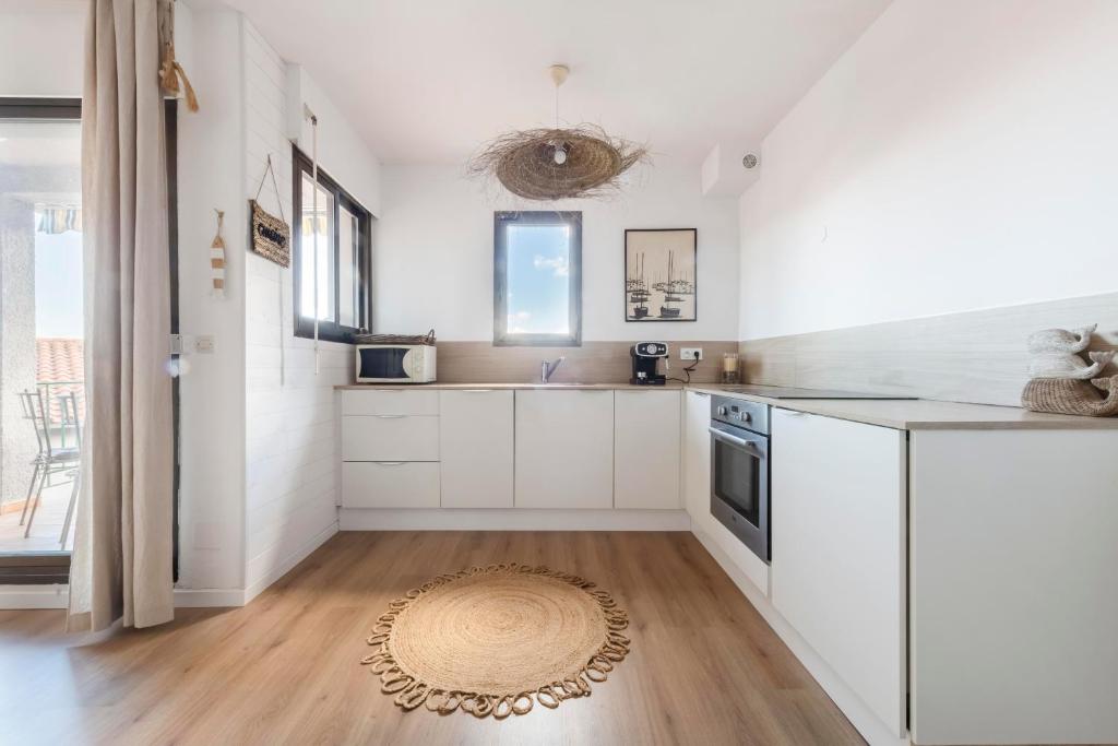 kuchnia z białymi szafkami i dywanem na podłodze w obiekcie Le Petit Colliourenc - Apt climatisé avec terrasse w mieście Collioure