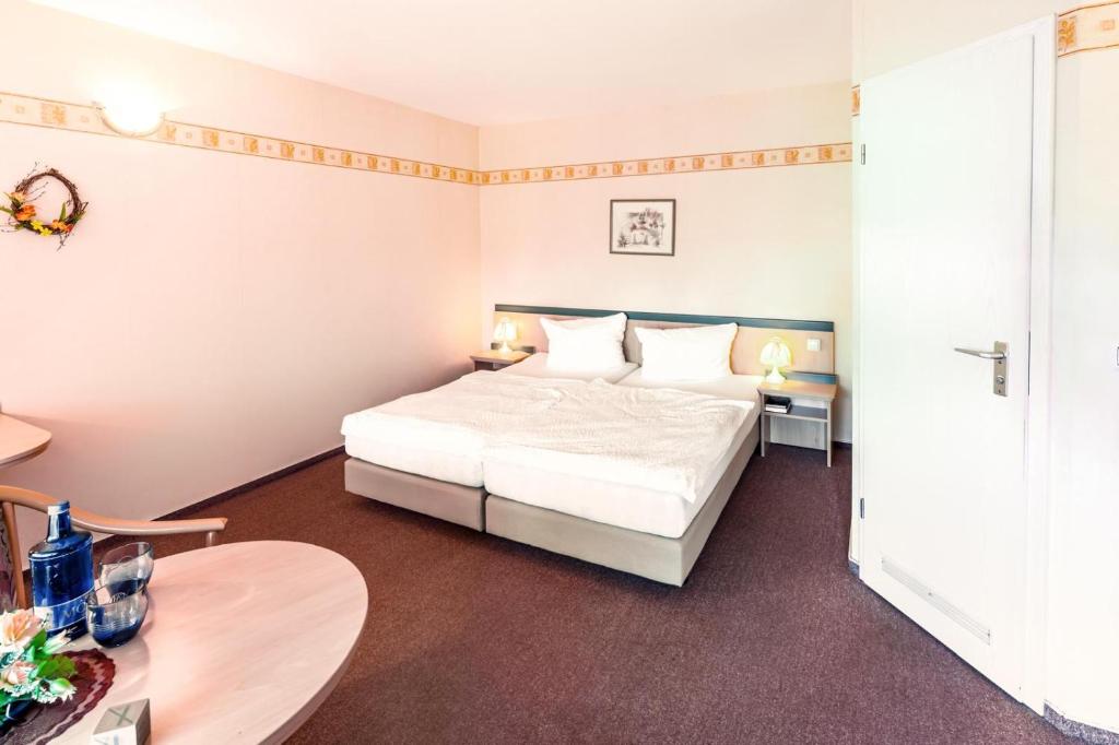 a hotel room with a bed and a table at Landhotel Lindengarten in Kleinzerlang