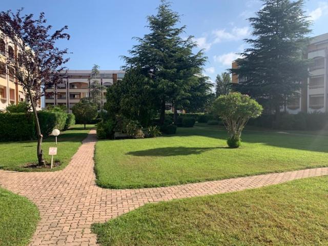 une passerelle en briques dans un parc arboré et un bâtiment dans l'établissement Centre Capitou avec jardin et piscine, à Mandelieu-la-Napoule