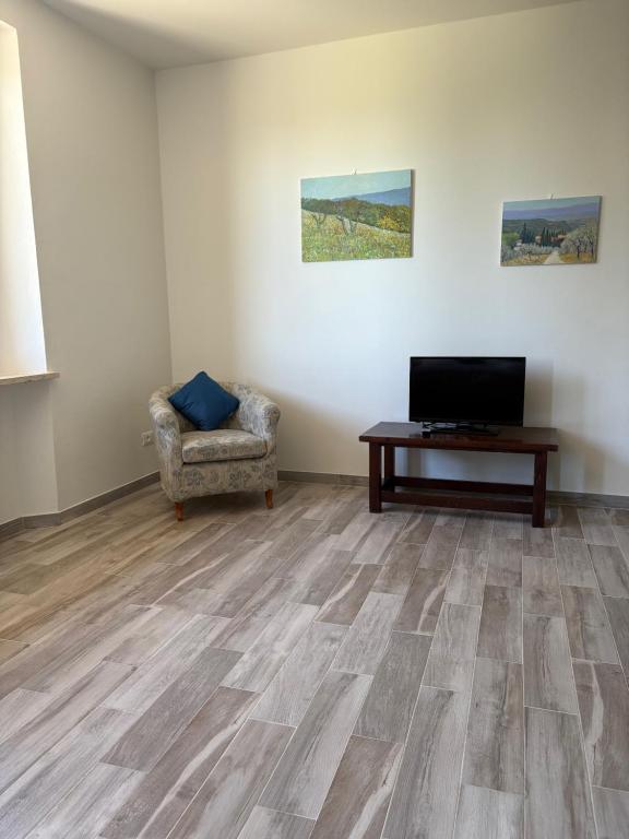 salon z telewizorem, krzesłem i stołem w obiekcie Casalchino-Fattoria La Torre w mieście San Gimignano