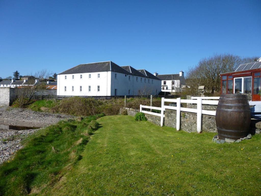 a field with a white fence and a building at Port Charlotte Youth Hostel in Port Charlotte