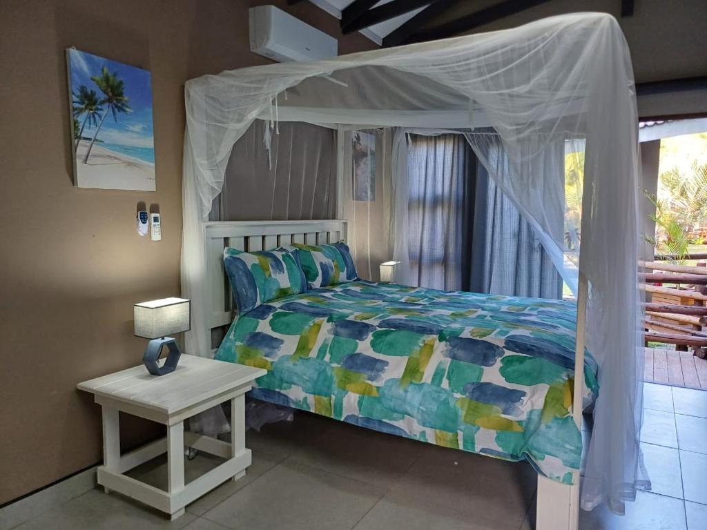 Un dormitorio con una cama con dosel y una mesa. en Bella Vida, en Matango