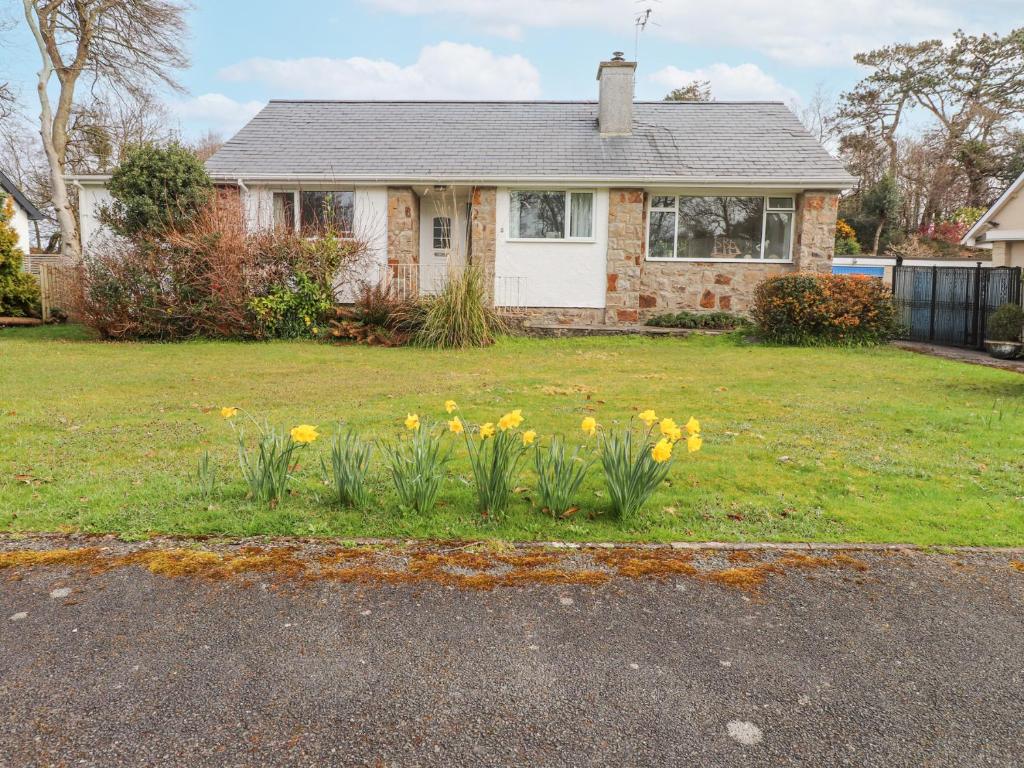 a house with a bunch of flowers in the yard at 3 Glyn Y Mor in Pwllheli