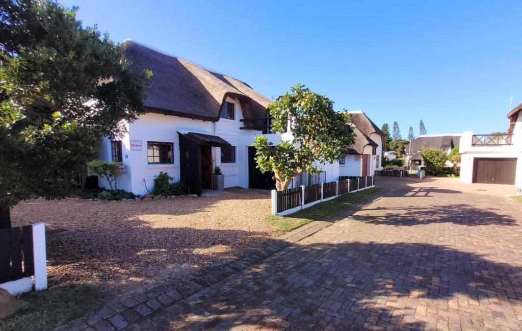 un edificio blanco con techo de paja en Charming 3 Bedroom Home in St Francis Bay, en Marina Glades