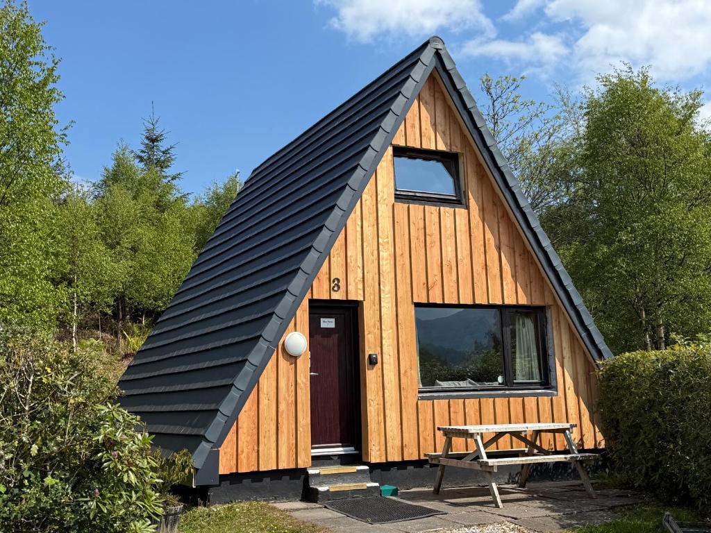 a small cabin with a black roof at 1 Bedroom Cabin with Mountain & Loch Views - Quiet Location between Glencoe & Ben Nevis in Onich