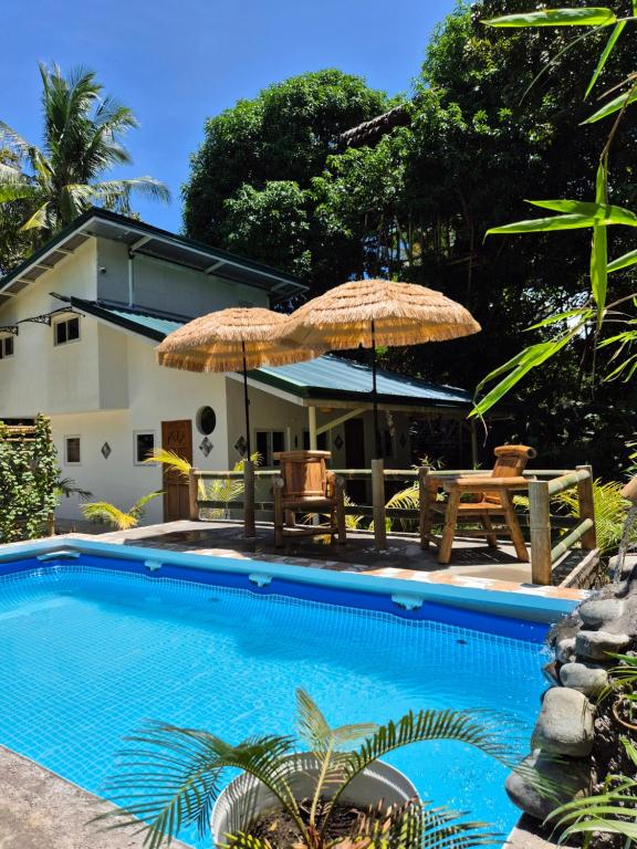 a pool with two umbrellas and two tables and chairs at Amazing Ocean View Treehouse & Pool in Puerto Princesa City