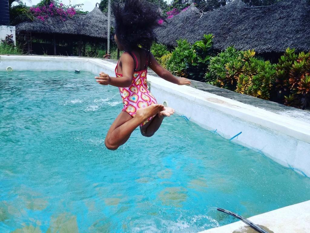 a little girl jumping into a swimming pool at Travellers Inn Resort Malindi in Malindi