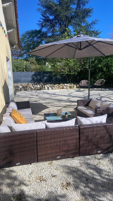 un canapé en osier marron assis sous un parasol dans l'établissement Gite de la Plaine, à Cubjac