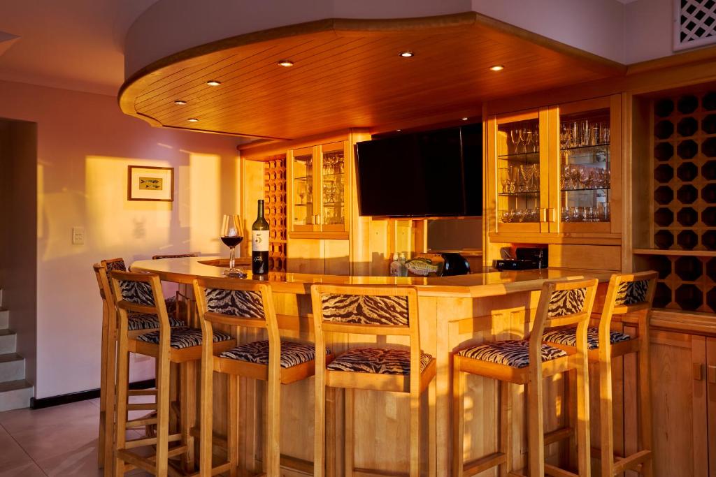 a kitchen with a bar with chairs and a tv at 42 On Strathmore in Cape Town