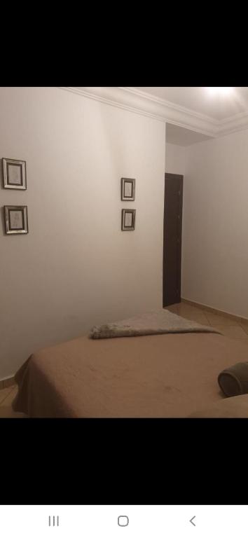 a bedroom with a bed with four pictures on the wall at Appartement à côté la plage in Oulad Akkou
