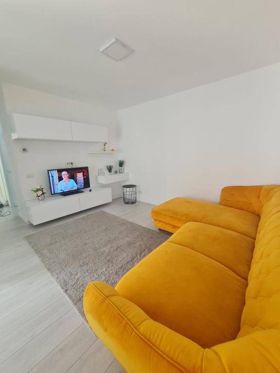 sala de estar con sofá amarillo y TV en Glamour, en Oradea