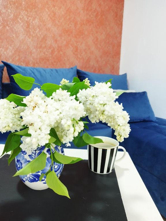 a vase of white flowers and a cup of coffee at Apartament Warszawska Centrum in Mrągowo