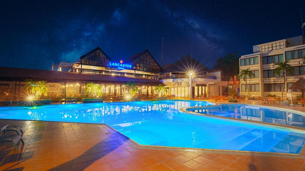 a large swimming pool in front of a building at night at Lancaster Accra in Accra