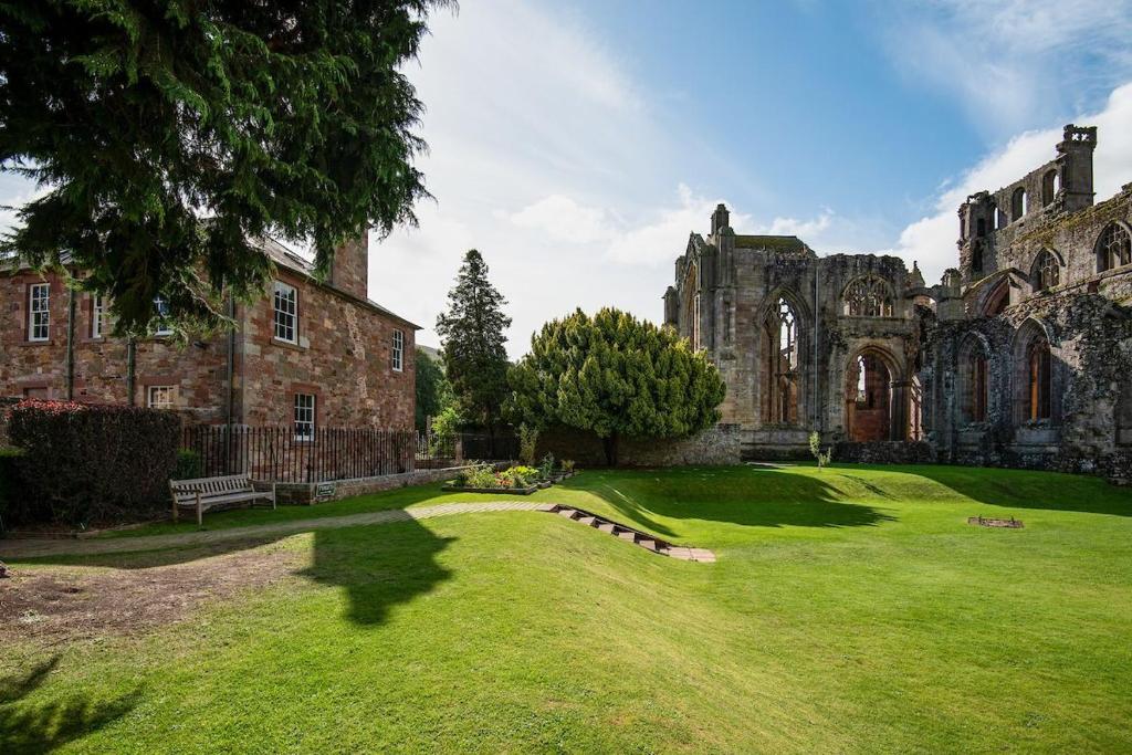 an old castle with a grass yard in front of it at Cloister House in Melrose