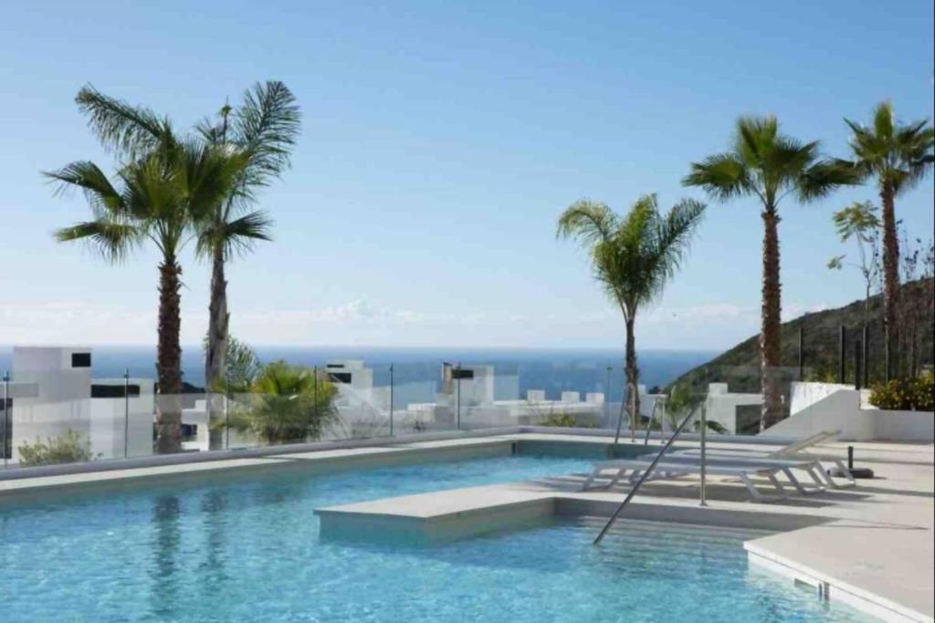 a swimming pool with palm trees and the ocean at 812 ALM Luxury aparment in Palo Alto, Marbella in Ojén