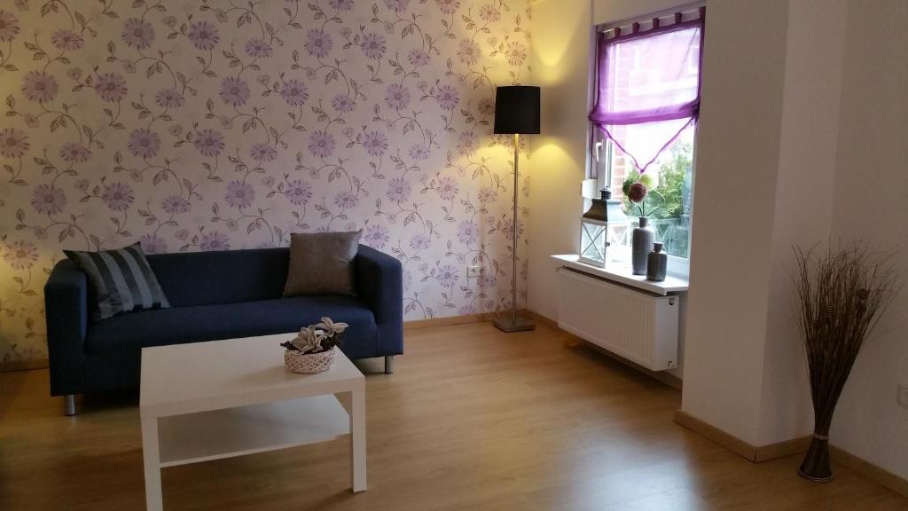 ein Wohnzimmer mit einem blauen Sofa und einem Fenster in der Unterkunft Ferienhaus Rheiderland in Ditzumerverlaat